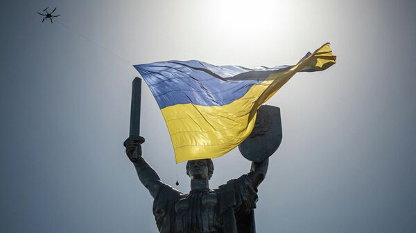 Украинский флаг в небе над монументом Родина-мать в Киеве