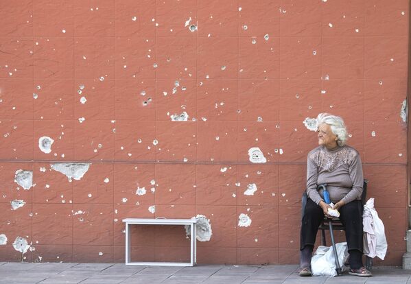 Женщина сидит на улице в центре Мариуполя