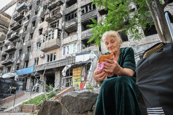 Женщина ест чебурек во дворе дома в Мариуполе