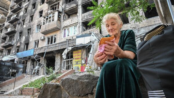 Женщина ест чебурек во дворе дома в Мариуполе