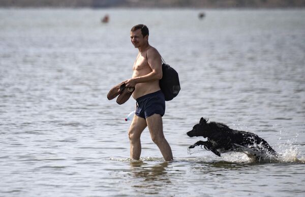 Мужчина с собакой на городском пляже в Мариуполе