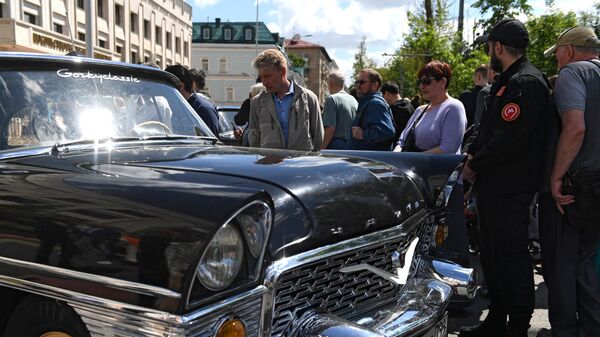 Люди рассматривают ГАЗ - 13 Чайка  на параде ретротранспорта в Москве