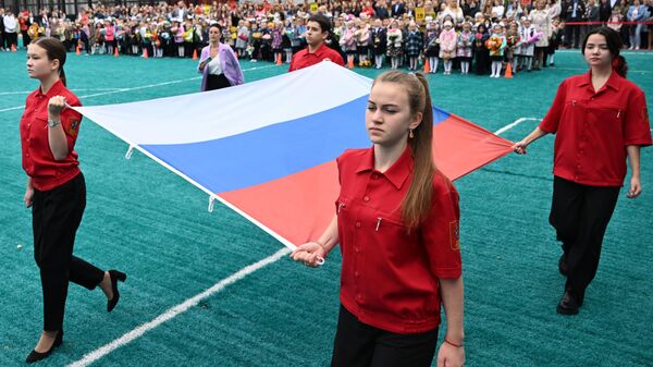 Учащиеся во время церемонии поднятия государственного флага России на торжественной линейке в День знаний, проходящей в школе №158 в Москве