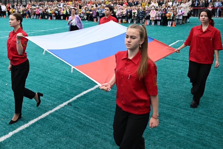 Учащиеся во время церемонии поднятия государственного флага России на торжественной линейке в День знаний, проходящей в школе №158 в Москве