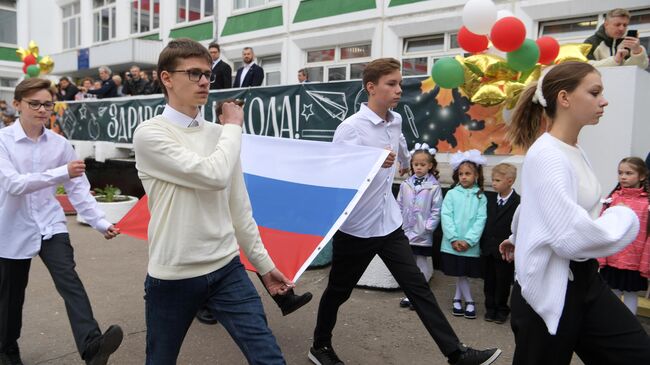 Учащиеся во время церемонии поднятия государственного флага России на торжественной линейке в День знаний, проходящей в школе №1619 имени М. И. Цветаевой в Москве