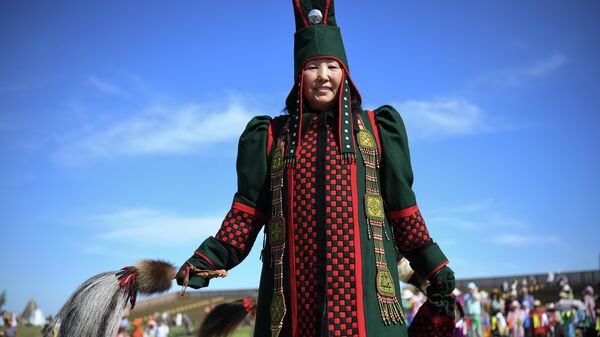Женщина в национальном костюме и с дэйбииром на праздновании традиционного якутского праздника Ысыах Туймаады в местности Ус Хатын недалеко от Якутска