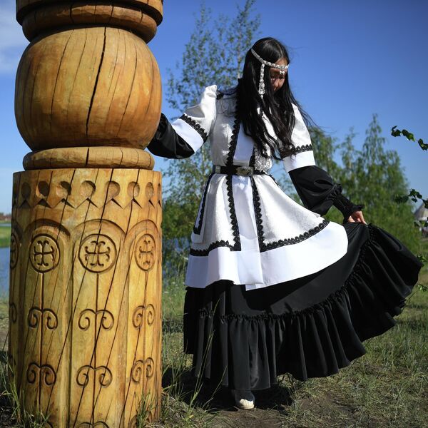 Девушка в национальном костюме у ритуального столба на праздновании традиционного якутского праздника Ысыах Туймаады в местности Ус Хатын недалеко от Якутска