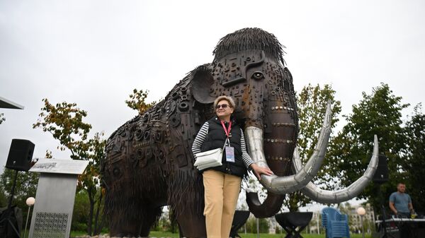 A participant of the Eastern Economic Forum in Vladivostok photographed next to a mammoth statue