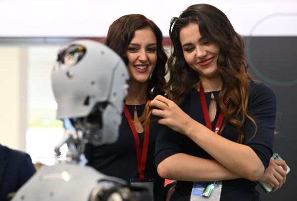 Девушки рассматривают сервисного робота-промоутера Алекса на Восточном  экономическом форуме во Владивостоке