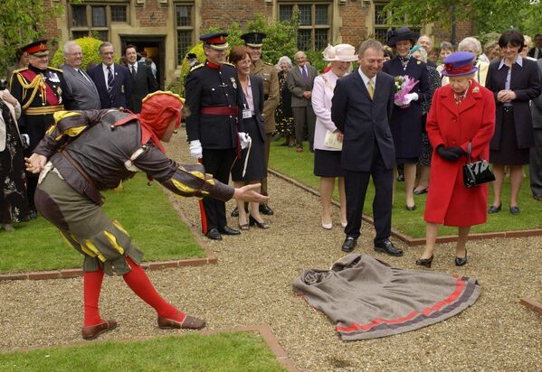 Артист разыгрывает сценку перед британской королевой Елизаветой II в особняке Истбери 
