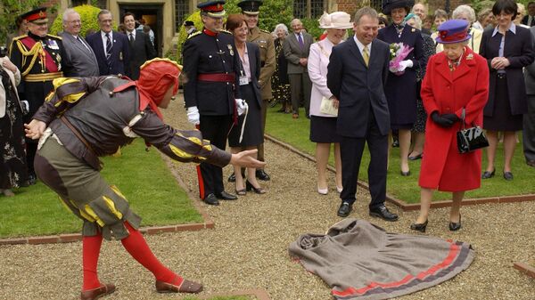 Артист разыгрывает сценку перед британской королевой Елизаветой II в особняке Истбери 