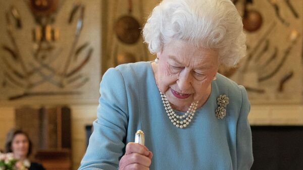 Королева Великобритании Елизавета II разрезает торт, чтобы отпраздновать начало семидесятой годовщины ее правления