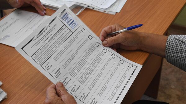 Избиратель держит в руках бюллетень на избирательном участке