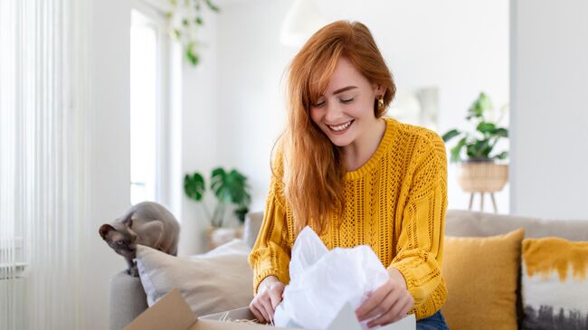 Девушка распаковывает посылку Девушка распаковывает посылку