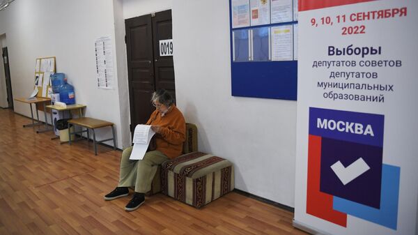 Женщина читает бюллетень на избирательном участке в Москве