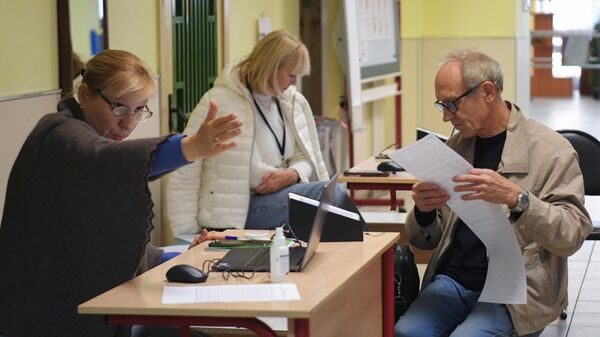 Мужчина получает бюллетень для голосования на избирательном участке в Москве