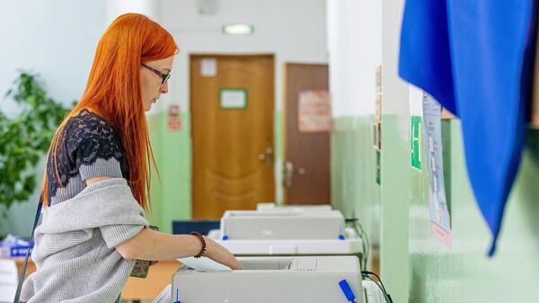Девушка голосует на выборах депутатов городской Думы на избирательном участке №915 во Владивостоке