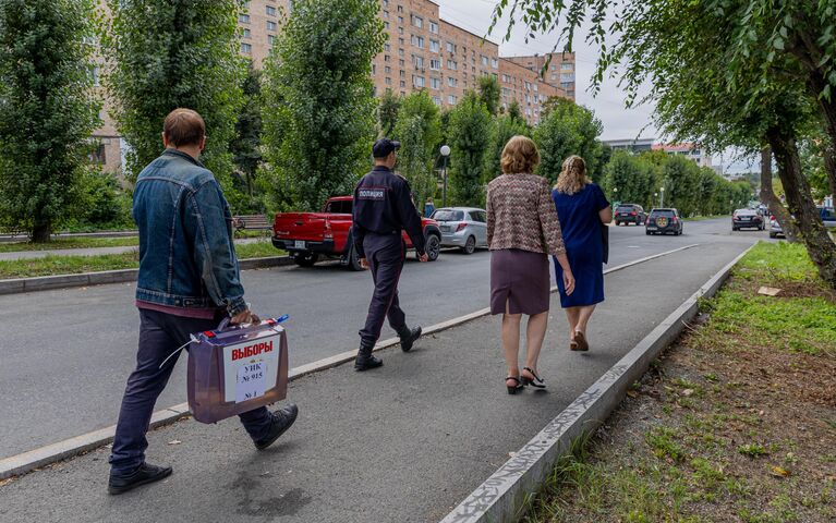 Члены избирательной комиссии и сотрудник полиции проводят выездное голосование на выборах депутатов городской Думы Владивостока