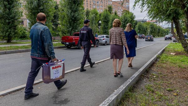 Члены избирательной комиссии и сотрудник полиции проводят выездное голосование на выборах депутатов городской Думы Владивостока
