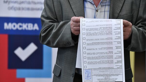 Житель Москвы изучает бюллетень на избирательном участке 