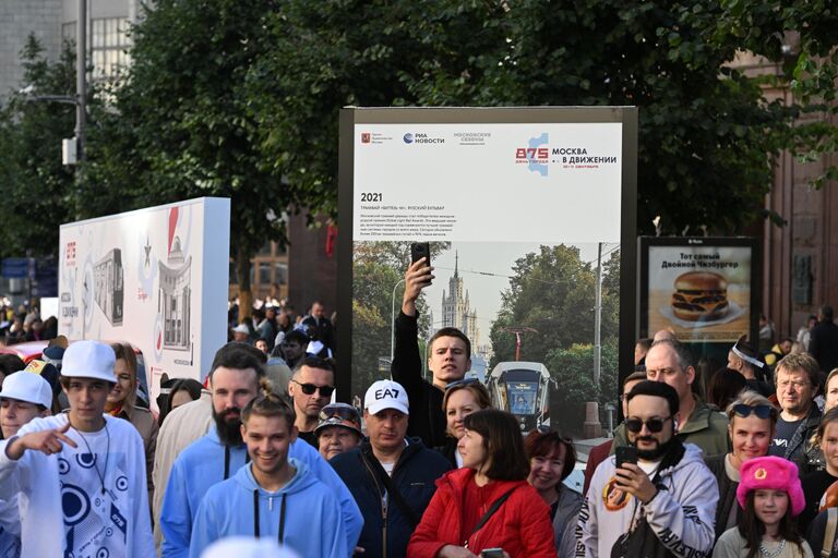 Люди возле стенда на фотовыставке агентства РИА Новости на Тверской улице в Москве