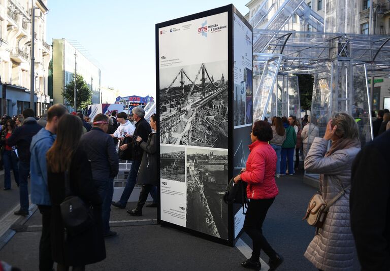 Люди возле стенда на фотовыставке агентства РИА Новости на Тверской улице в Москве