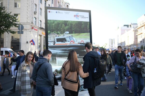 Люди возле стенда на фотовыставке агентства РИА Новости на Тверской улице в Москве