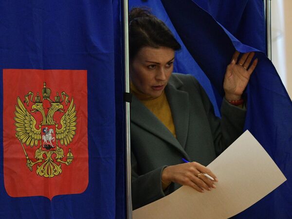 Женщина голосует на дополнительных выборах депутатов муниципальных советов Санкт-Петербурга на одном из избирательных участков города