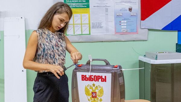 Сотрудница избирательной комиссии во Владивостоке вскрывает переносную урну для дальнейшего подсчета бюллетеней после завершения голосования