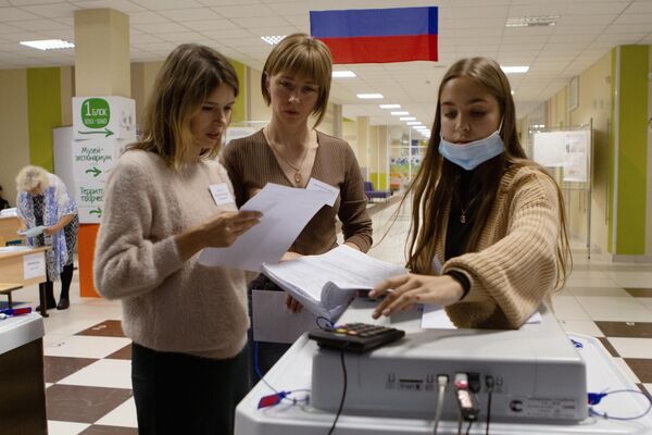 Сотрудники избирательного участка в Томске собирают данные по бюллетеням после завершения голосования на досрочных выборах губернатора области