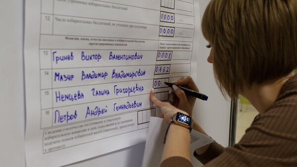 Сотрудница избирательного участка в Томске вносит данные по бюллетеням после завершения голосования на досрочных выборах губернатора области