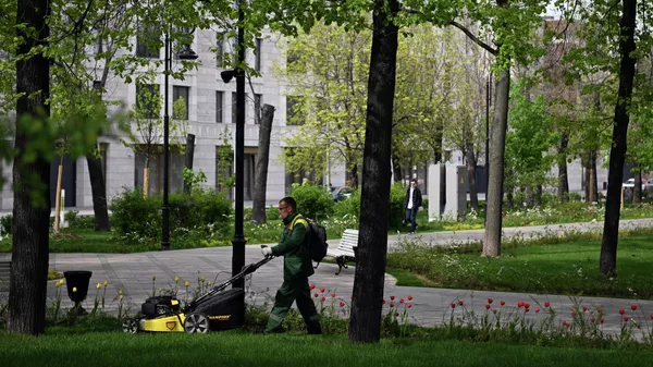 Сотрудник коммунальных служб косит траву в Репинском сквере в Москве