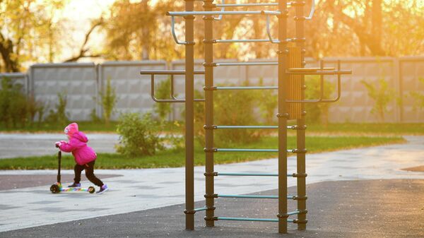Ребенок катается на самокате у спортивной площадки