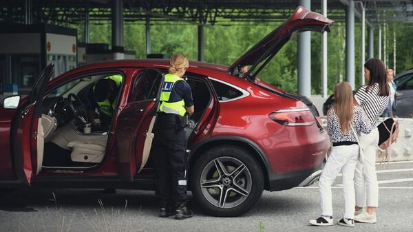 Сотрудник таможни проверяет автомобиль российских туристов на пограничном переходе Нуйямаа, Финляндия