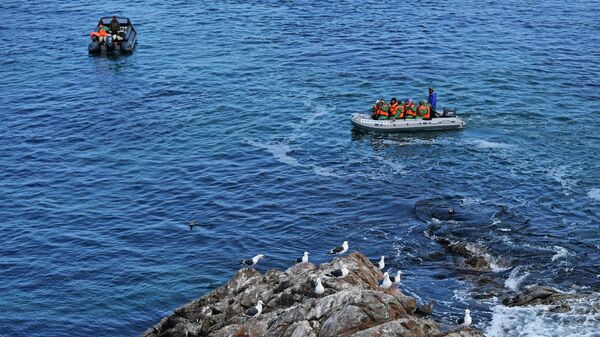 Лодки с туристами у подножия скалы Сивучья, где расположен заброшенный маяк Анива