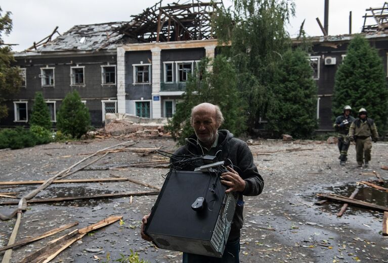 Мужчина с персональным компьютером на одной из улиц после обстрела ВСУ Перевальска