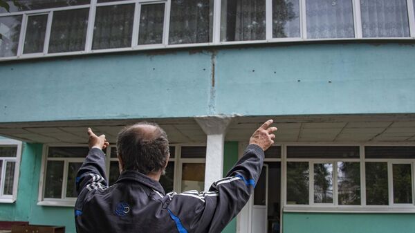 Мужчина показывает поврежденные в результате обстрела ВСУ стекла в детском саду в городе Васильевка Запорожской области