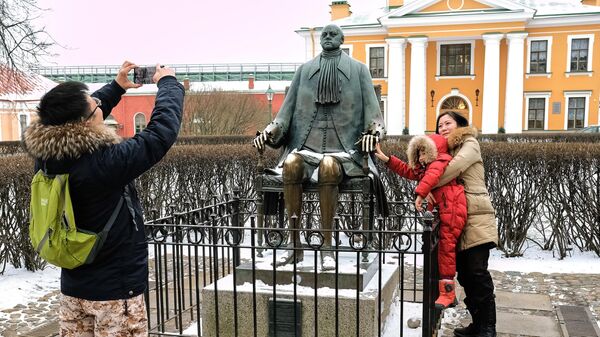 Иностранные туристы фотографируются у памятника Петру I на территории Петропавловской крепости в Санкт-Петербурге