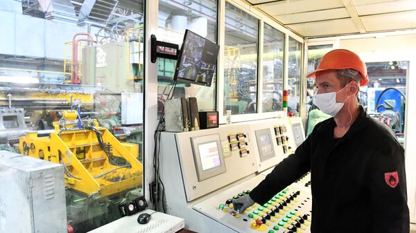 Рабочий за пультом управления в прессовом цехе Красноярского металлургического завода