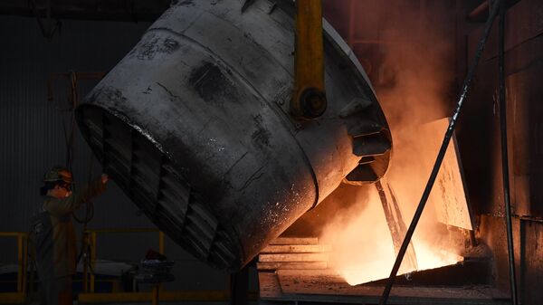 Рабочий заливает расплавленный металл в миксер для производства алюминиевых слитков в литейном цехе Красноярского алюминиевого завода компании Русал