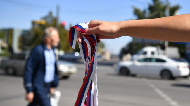 Волонтер движения Мы вместе раздает ленточки триколора в рамках подготовки к референдуму