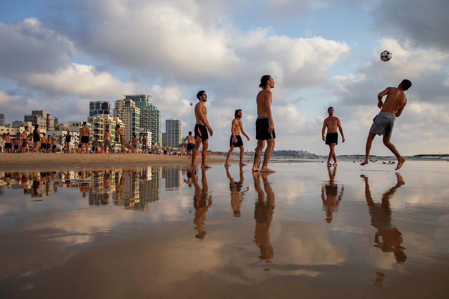 Люди играют в волейбол на пляже в Тель-Авиве