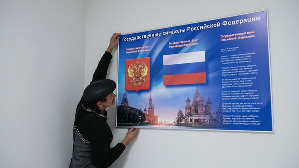 Рабочий вешает стенд во время подготовки к референдуму о присоединении к России ЛНР на одном из избирательных участков в Луганске