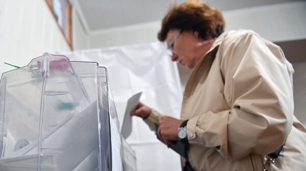 Женщина голосует на референдуме о присоединении Запорожской области к России на избирательном участке на Мелитопольском предприятии