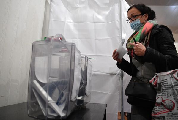 Женщина голосует на референдуме о присоединении Запорожской области к России на избирательном участке на Мелитопольском предприятии