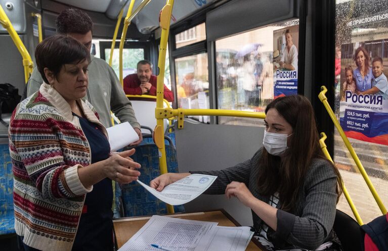 Женщина на выездном голосовании в салоне автобуса в Луганске на референдуме о вступлении Луганской народной республики в состав РФ