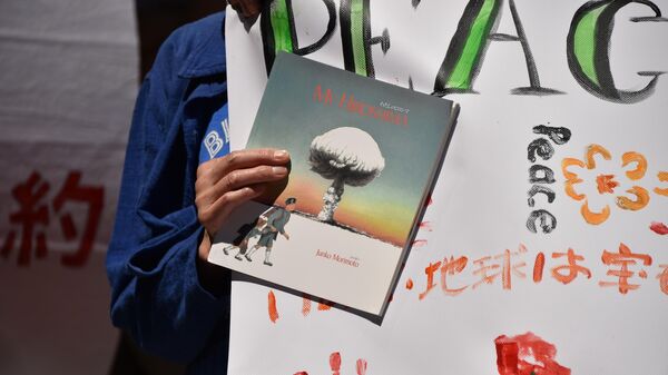 Участник митинга против ядерного оружия держит книгу с изображением ядерного взрыва