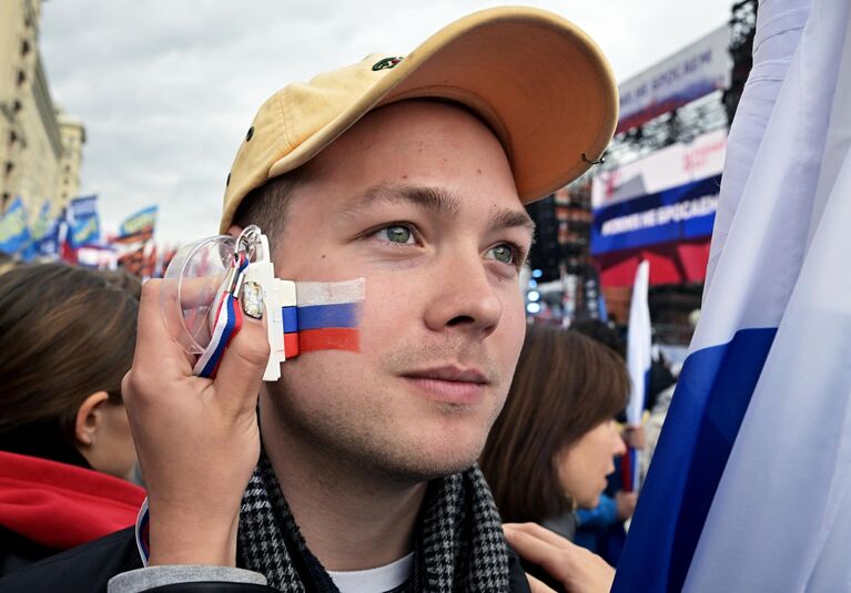 Молодой человек перед началом митинга Своих не бросаем на Манежной площади в Москве