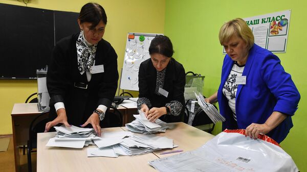 Члены участковой избирательной комиссии упаковывают бюллетени в сейф-пакеты
