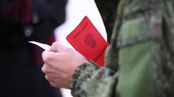 Военный билет в руках мужчины, призванного на воинскую службу в ходе частичной мобилизации